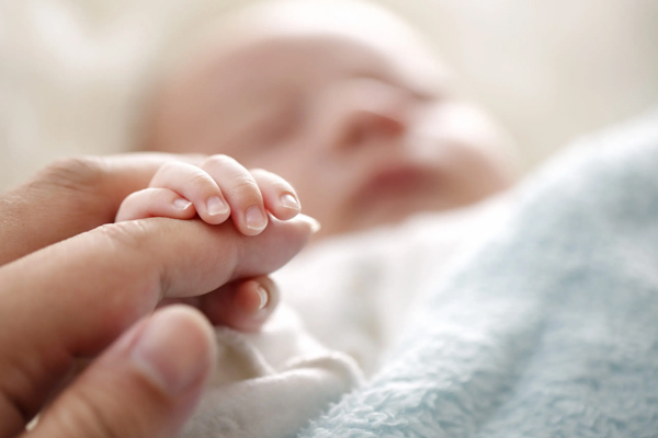 Sleeping baby clenches his parent's fingers; Soft focus and blurry